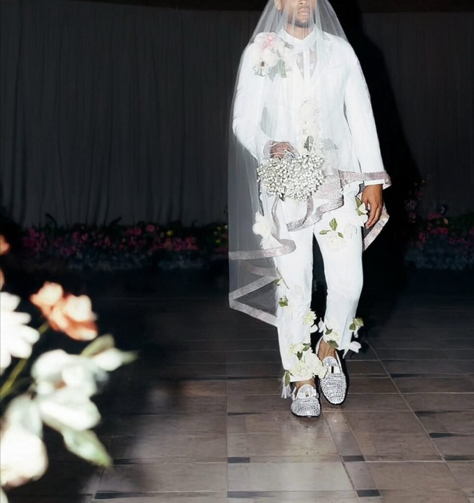 Person in white wedding attire with a veil, floral bouquet, and sparkly silver loafers.
