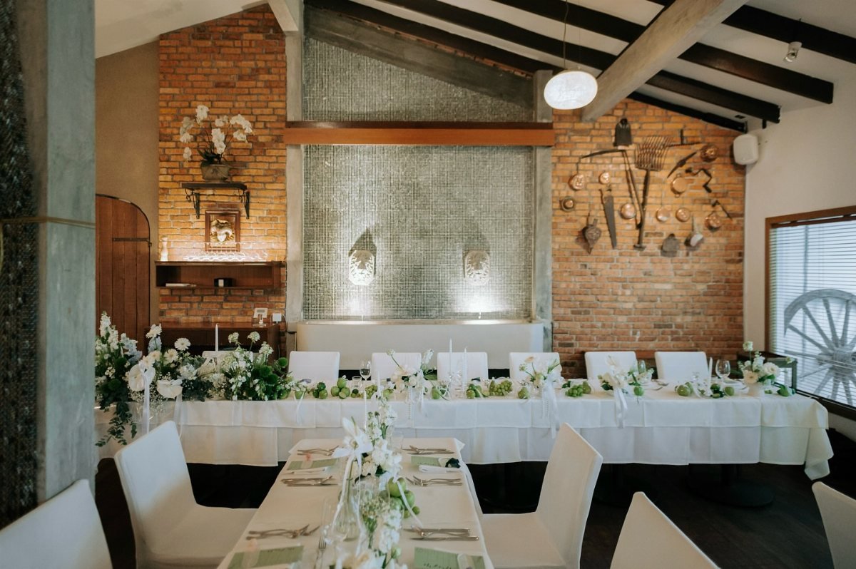 Wedding reception tables decorated with white linens and abundant green and white floral centerpieces.